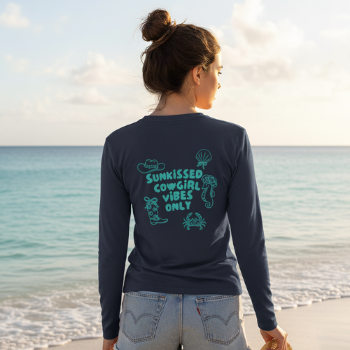 Woman wearing a navy long-sleeve shirt with a graphic design on the beach